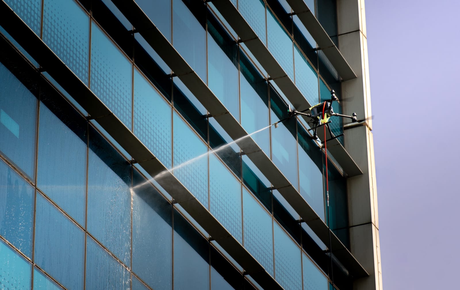 Drone washing a high-rise facade with a precision water jet